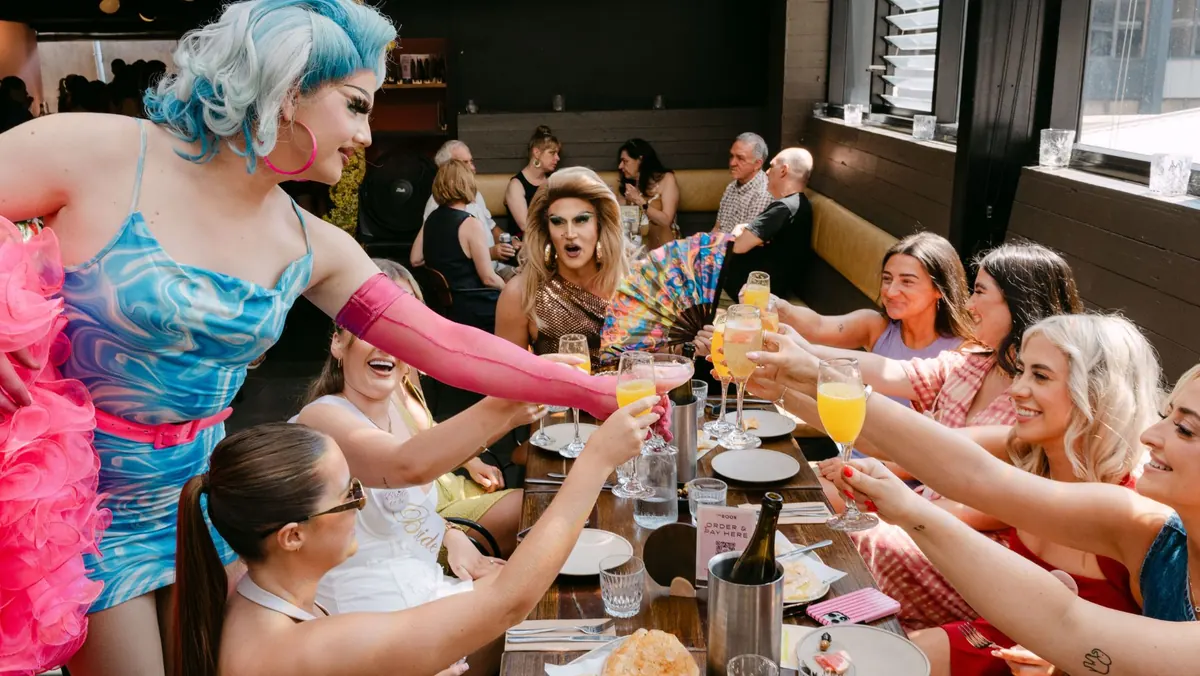 Drag performers hosting a long table of guests over bottomless brunch.